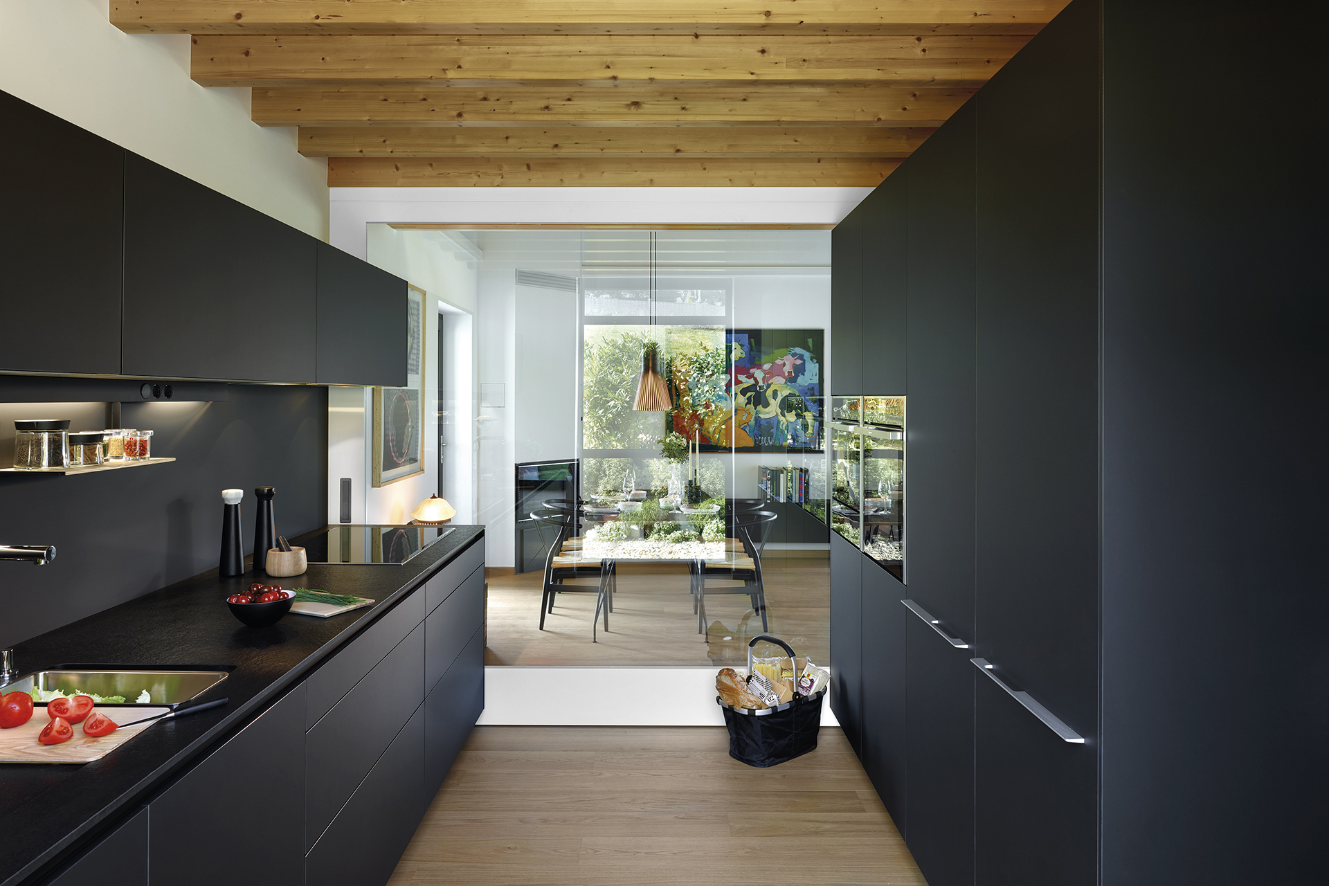 Black parallel kitchen that opens into the dining room, fitted with cabinets designed by Santos