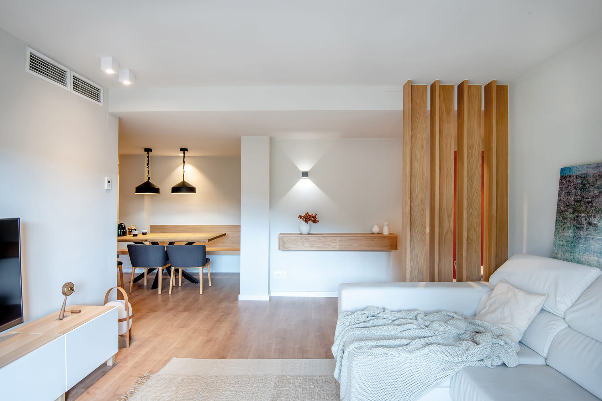 Salón con suelo de madera y sofá blanco