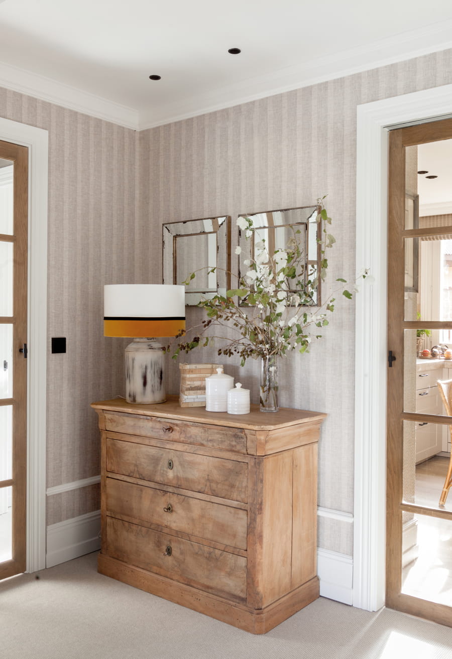 Entrance hall with antique chest of drawers and papered walls