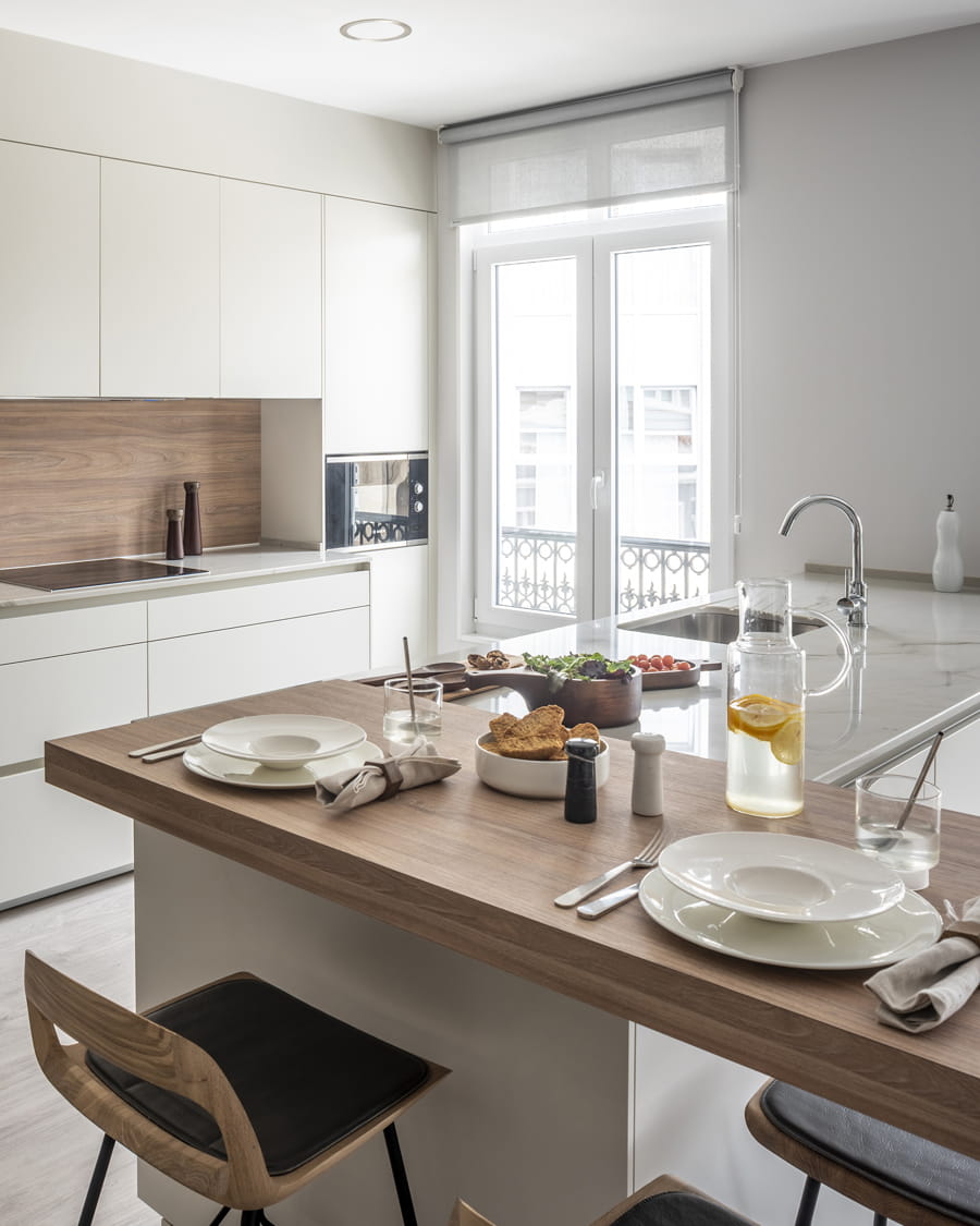 White kitchen with island and worktop-mounted bar in an elm finish