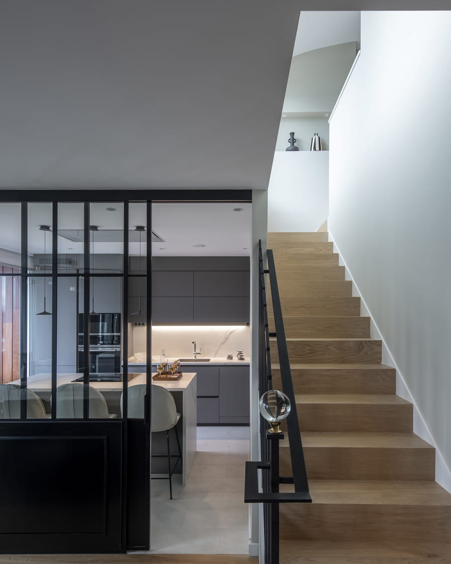 Grey kitchen that opens out to the stairs leading to the upper floor