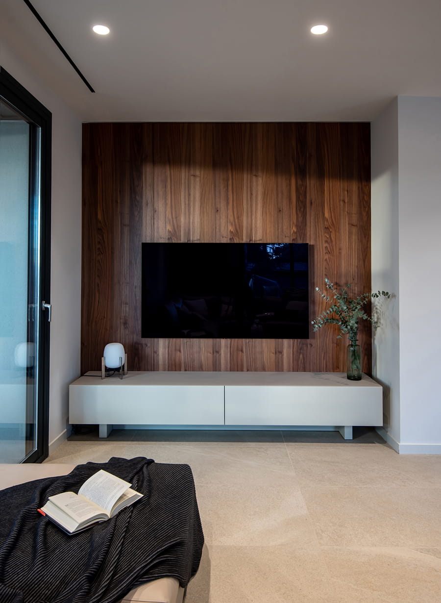 Sala de estar com televisão e móveis em branco e madeira