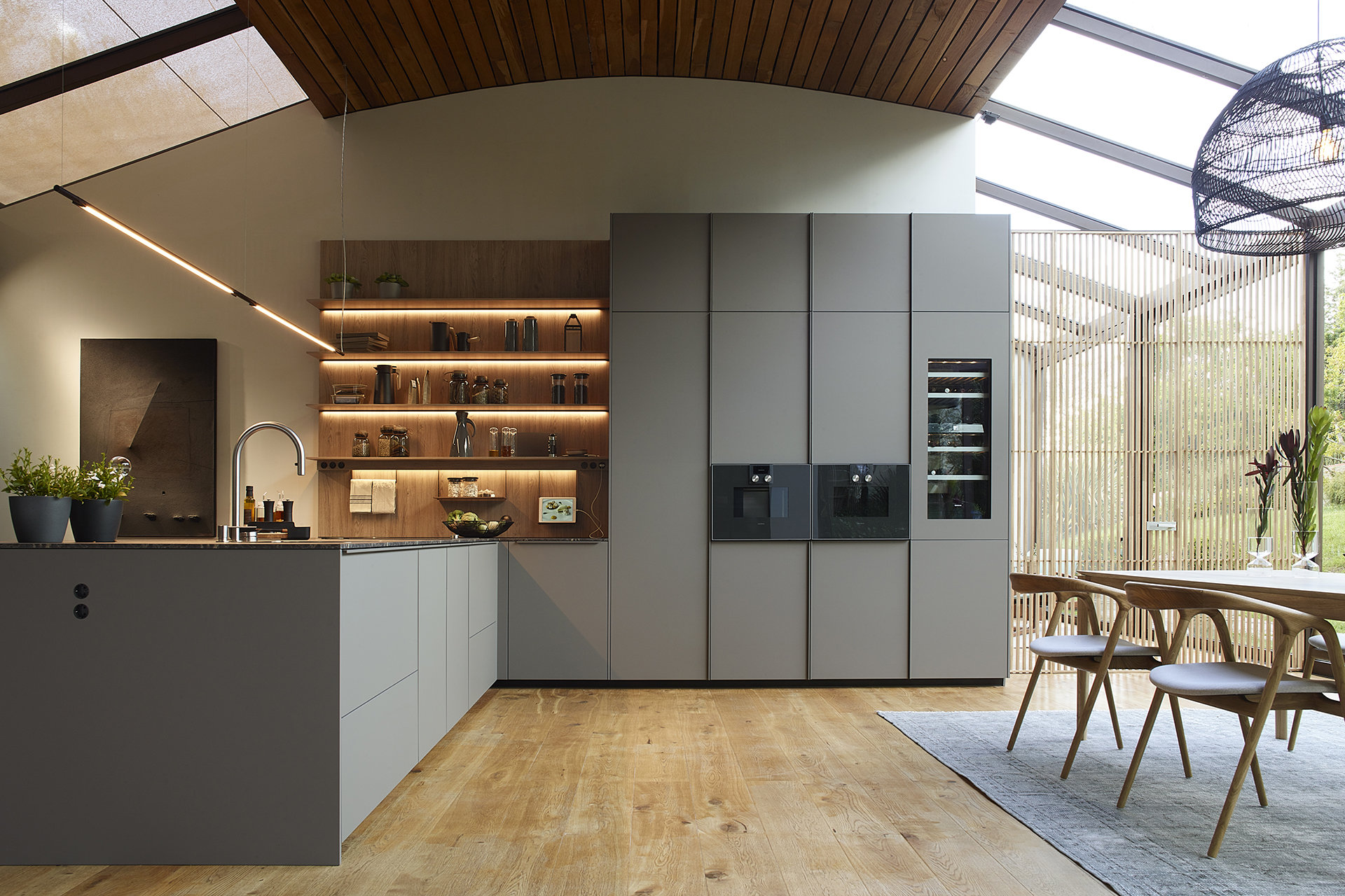 Cocina gris con península y estantería con iluminación