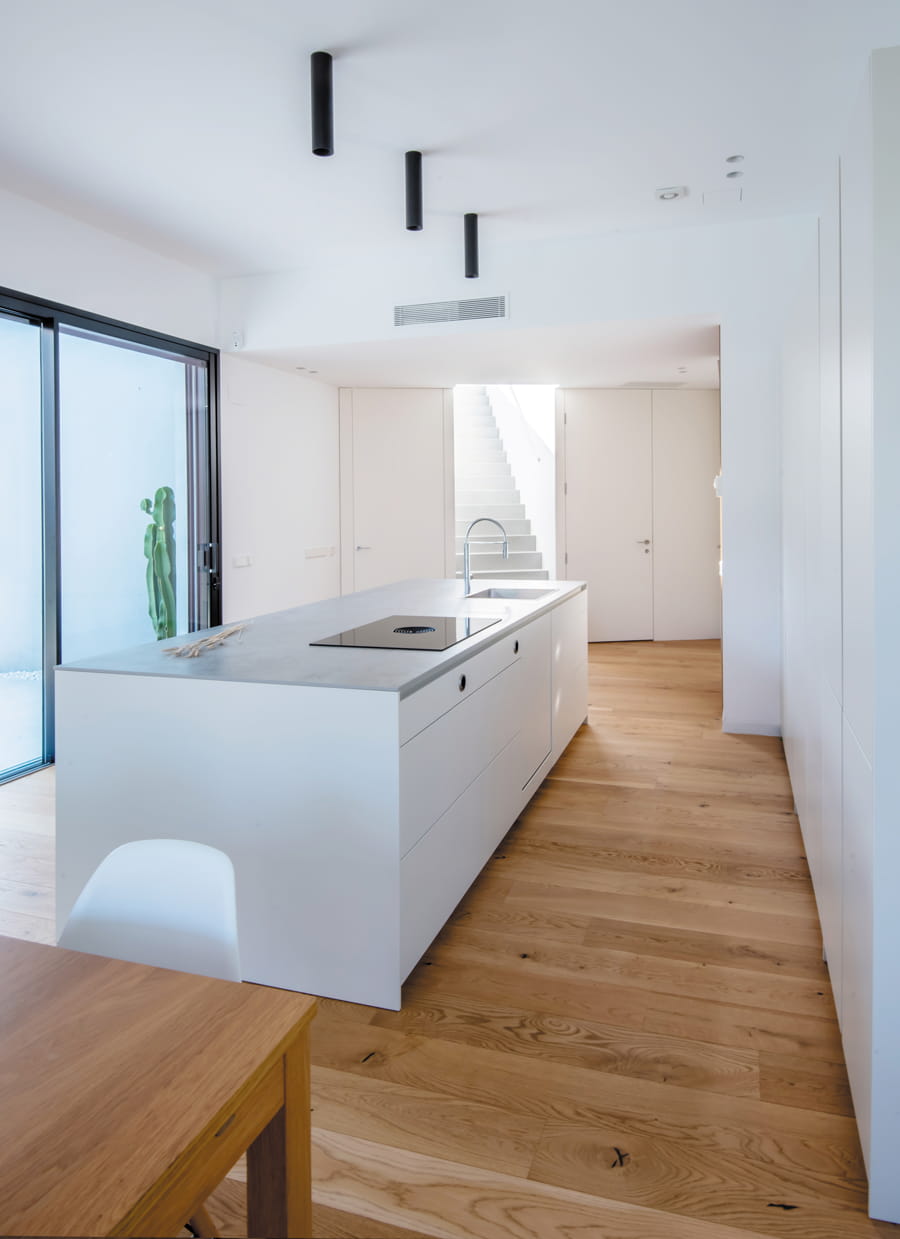 Cocina con isla blanca con portaplaca y fregadero