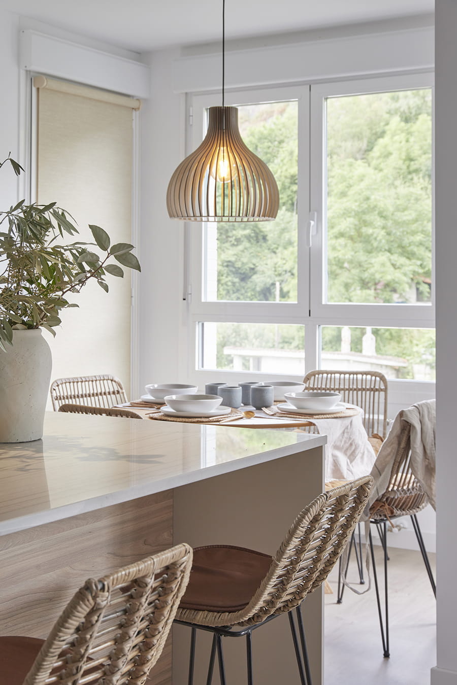 Eiland van open keuken naar de zit- en eetkamer, met opvallende hangende verlichting.