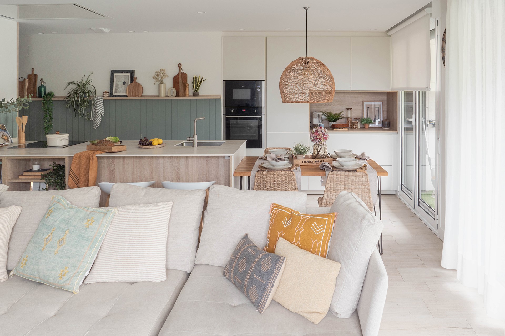 Cocina blanca y madera con isla, abierta al salón con zona de desayuno.