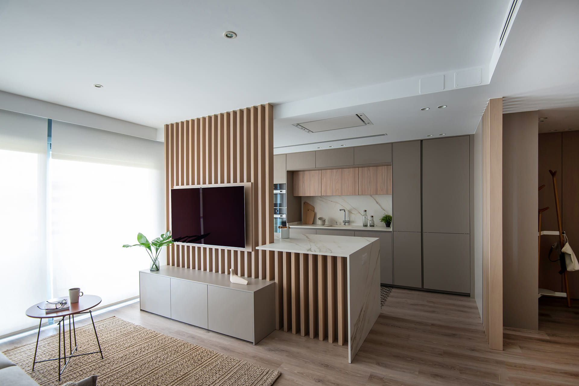 Parallel sand grey and light elm wood kitchen open to the living room.