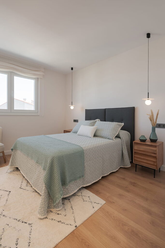 Minimalist bedroom with suspended lighting and wood flooring.
