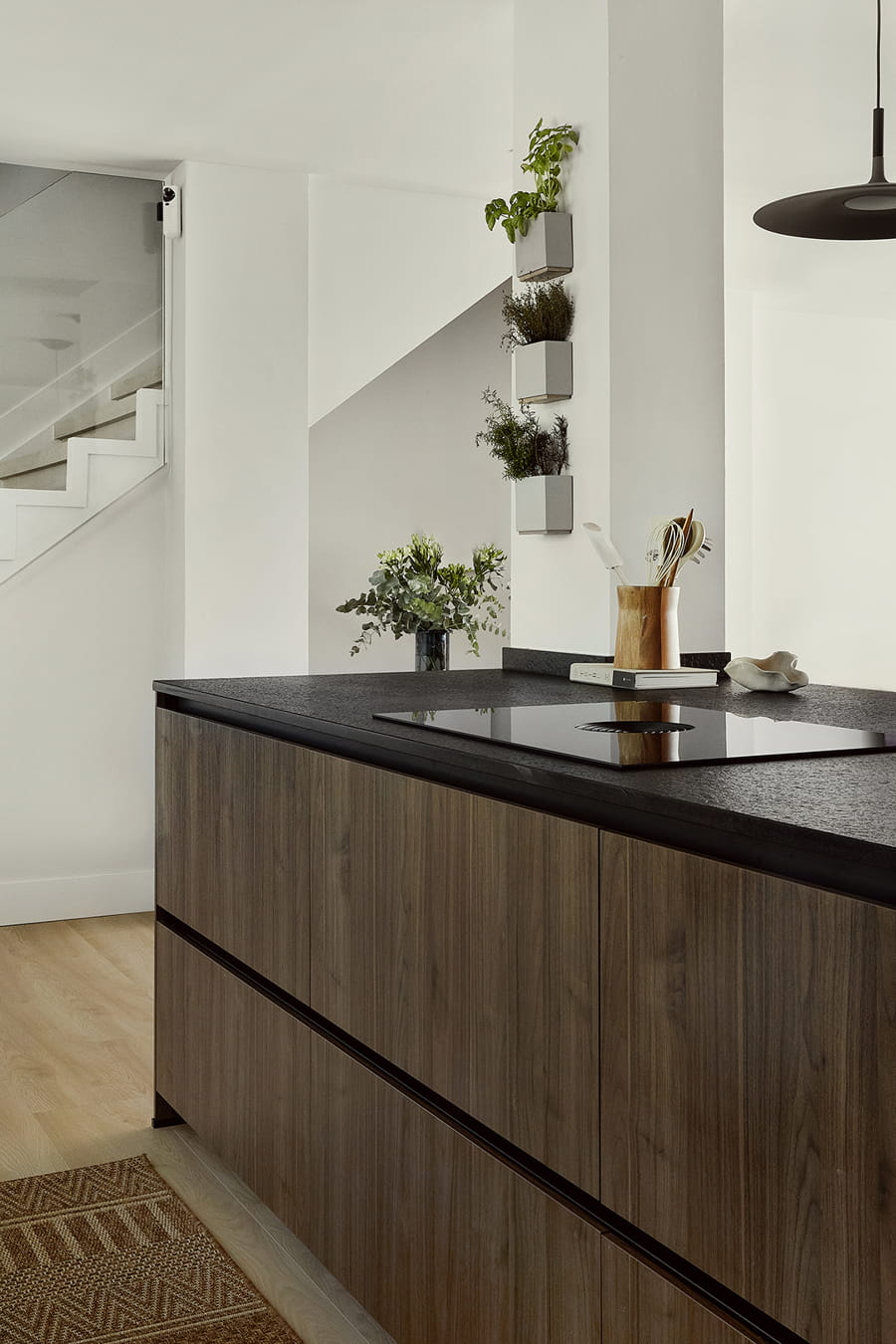 Grey kitchen island with black worktop and walnut cladding.