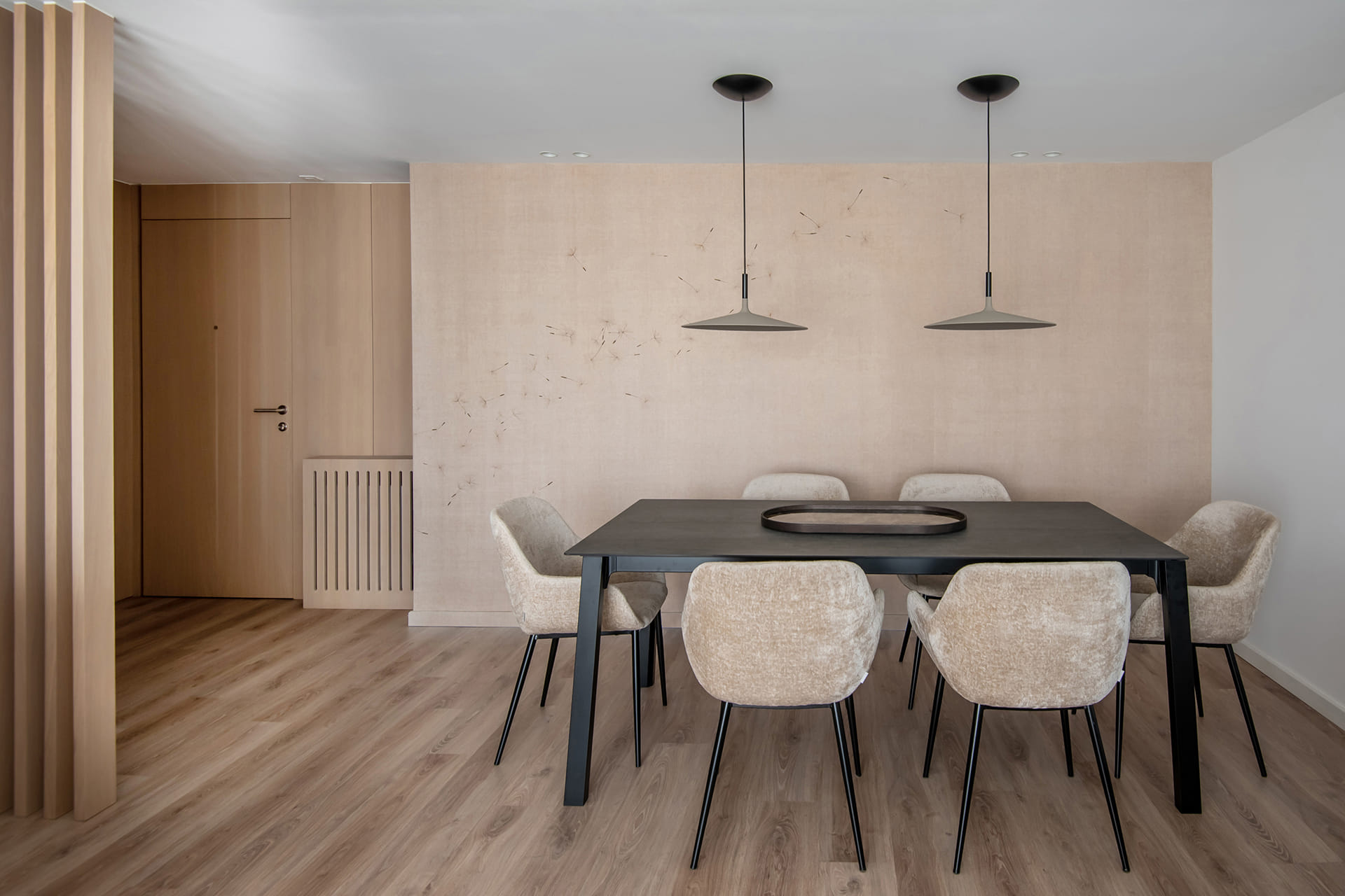 Black dining room table with suspended lighting and wood flooring.