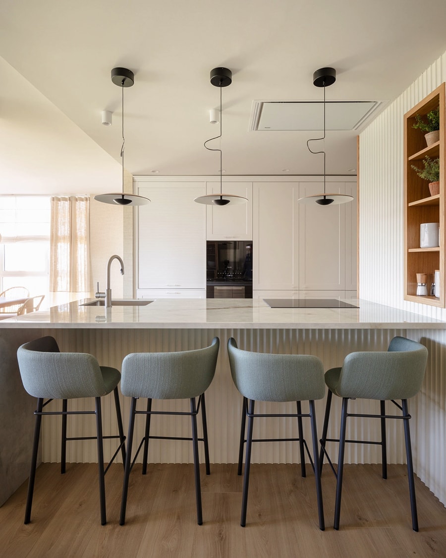 Peninsula with grey stools in white kitchen.