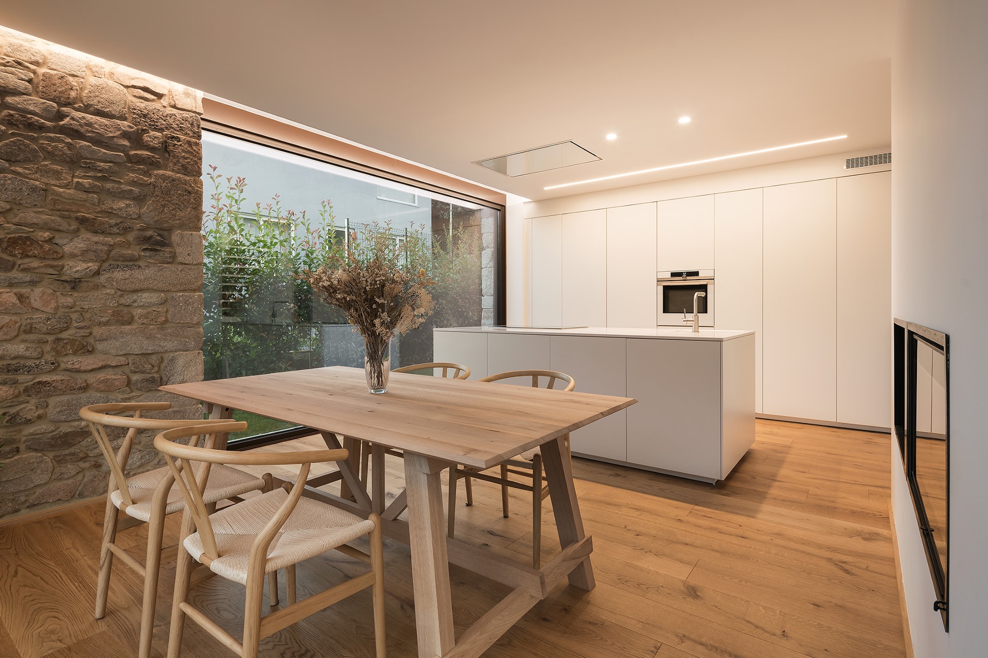 Cocina blanca Santos con isla abierta al comedor, en vivienda diseñada por Arnela Arquitectura.