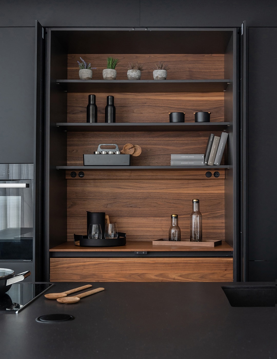 Armários coluna de cozinha na cor Preto Seda com acabamentos em madeira.