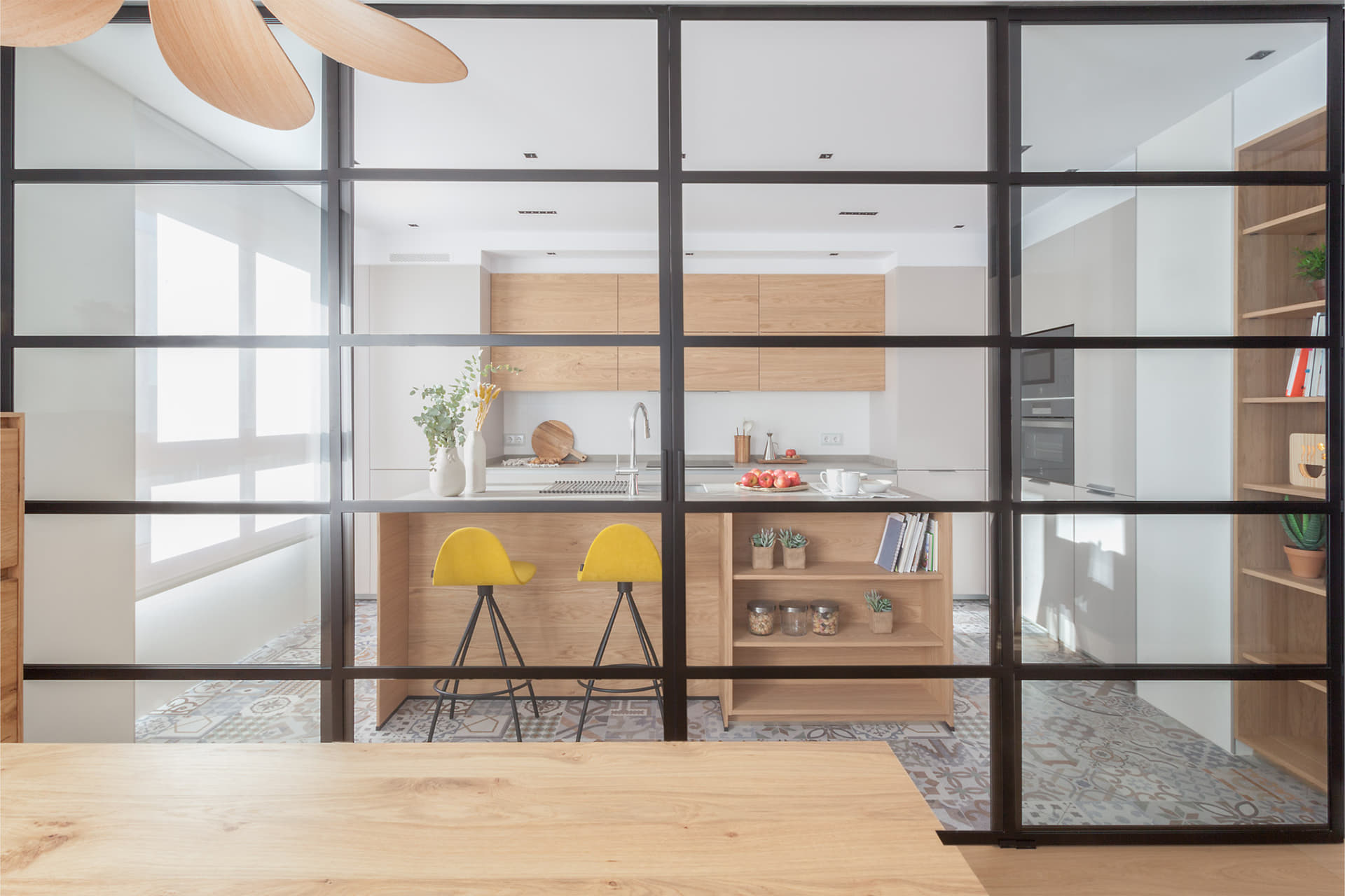 Cocina abierta al salón comedor con cerramiento acristalado e isla diseñada por Santos.