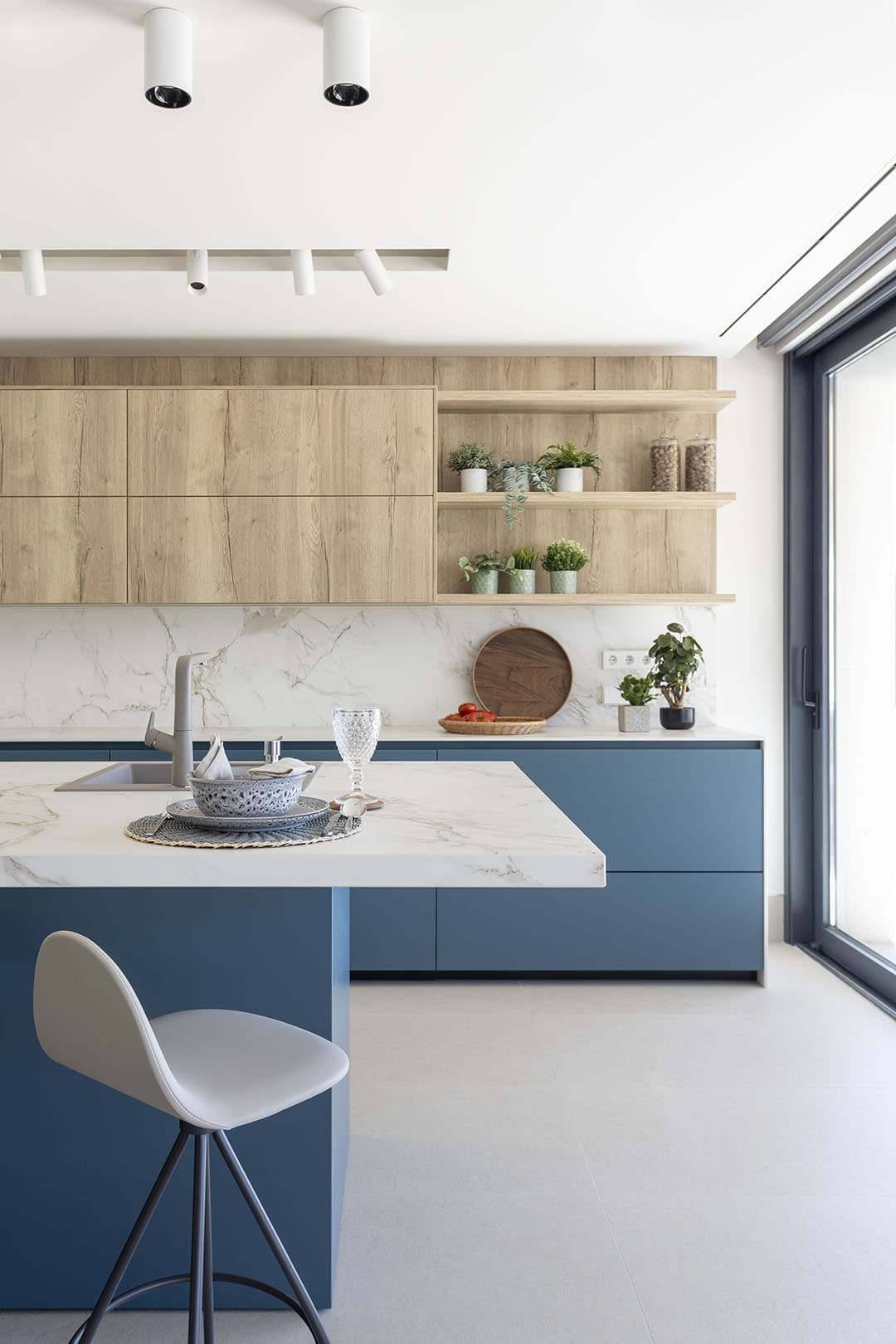 Cocina azul y madera con isla abierta al salón comedor diseñada por Santos.