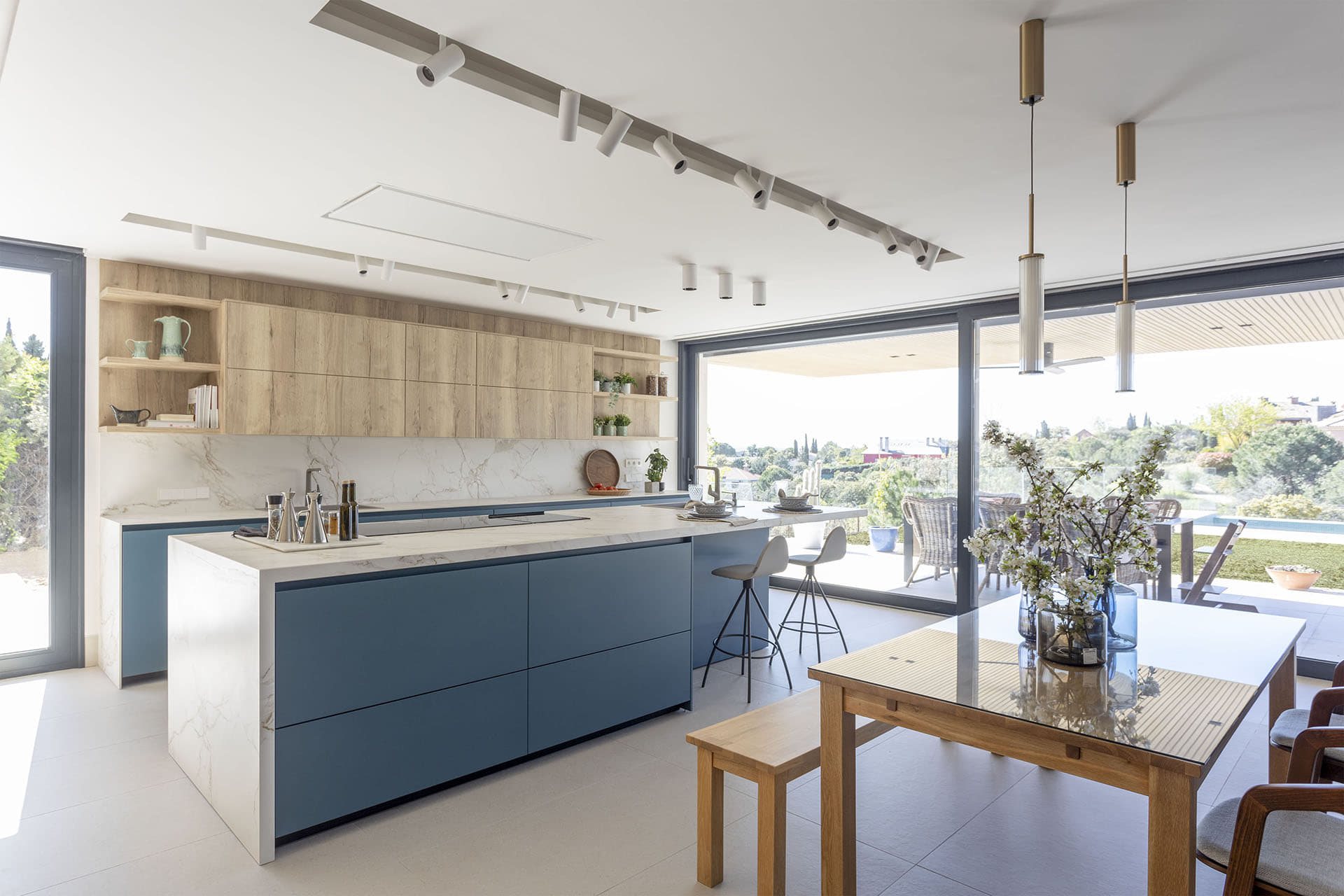 Cocina en azul y madera con isla abierta al salón diseñada por Santos.