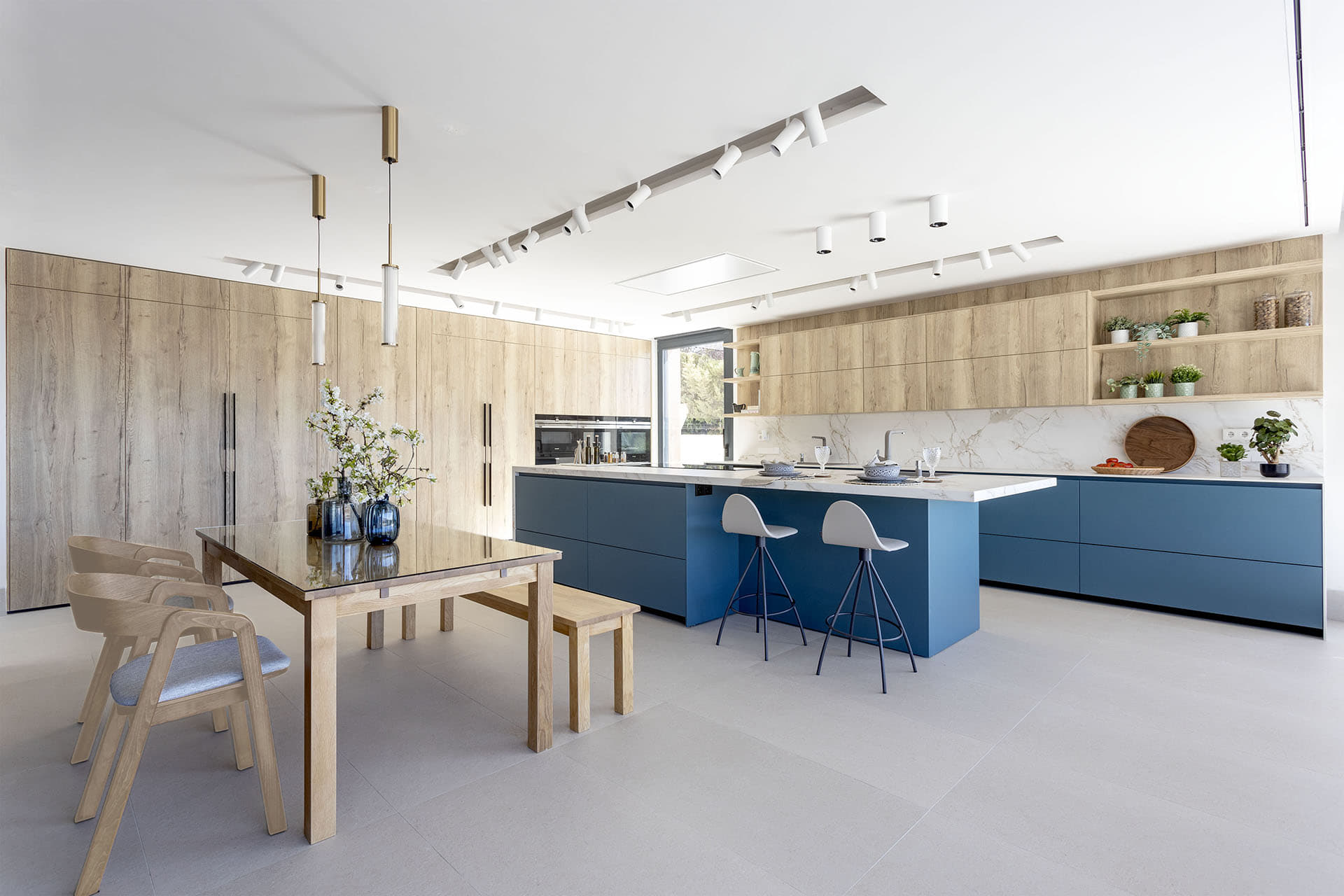 Cocina en azul y madera con isla y comedor diseñada por Santos.