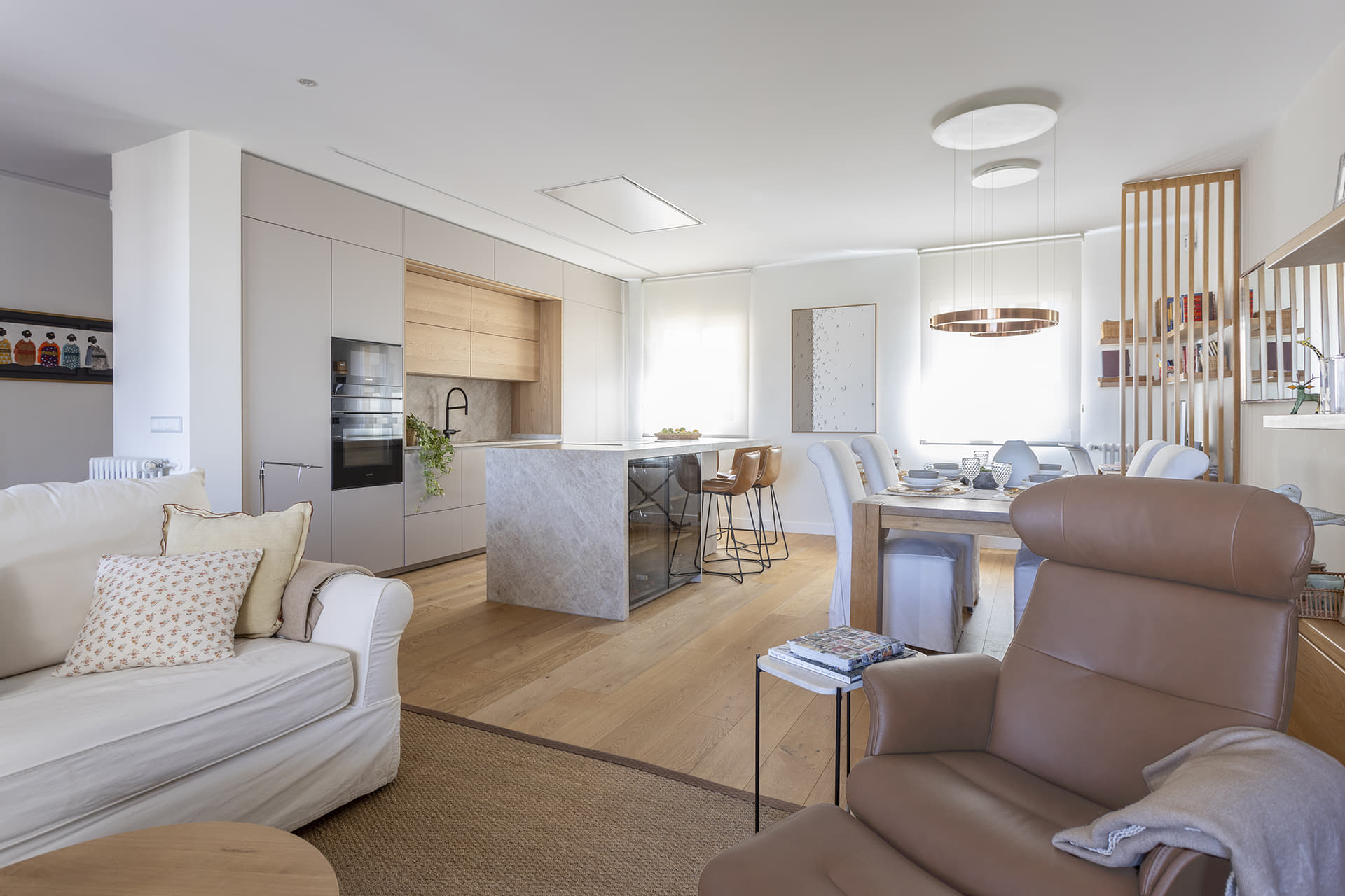 Cocina en blanco y madera integrada en zona de día diseñada por Santos.