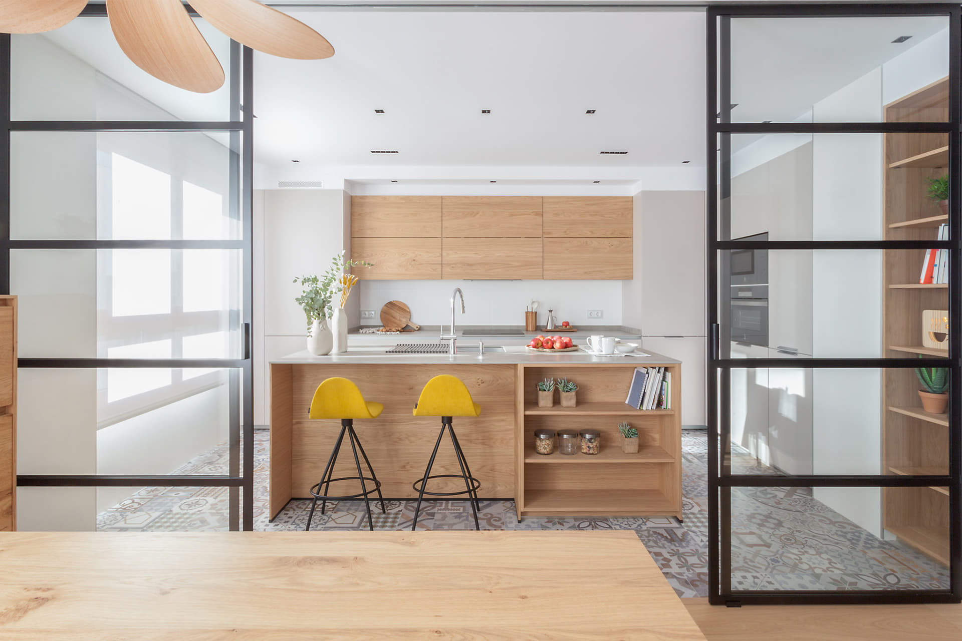 Cocina con isla abierta al salón comedor con cerramiento acristalado de Santos.