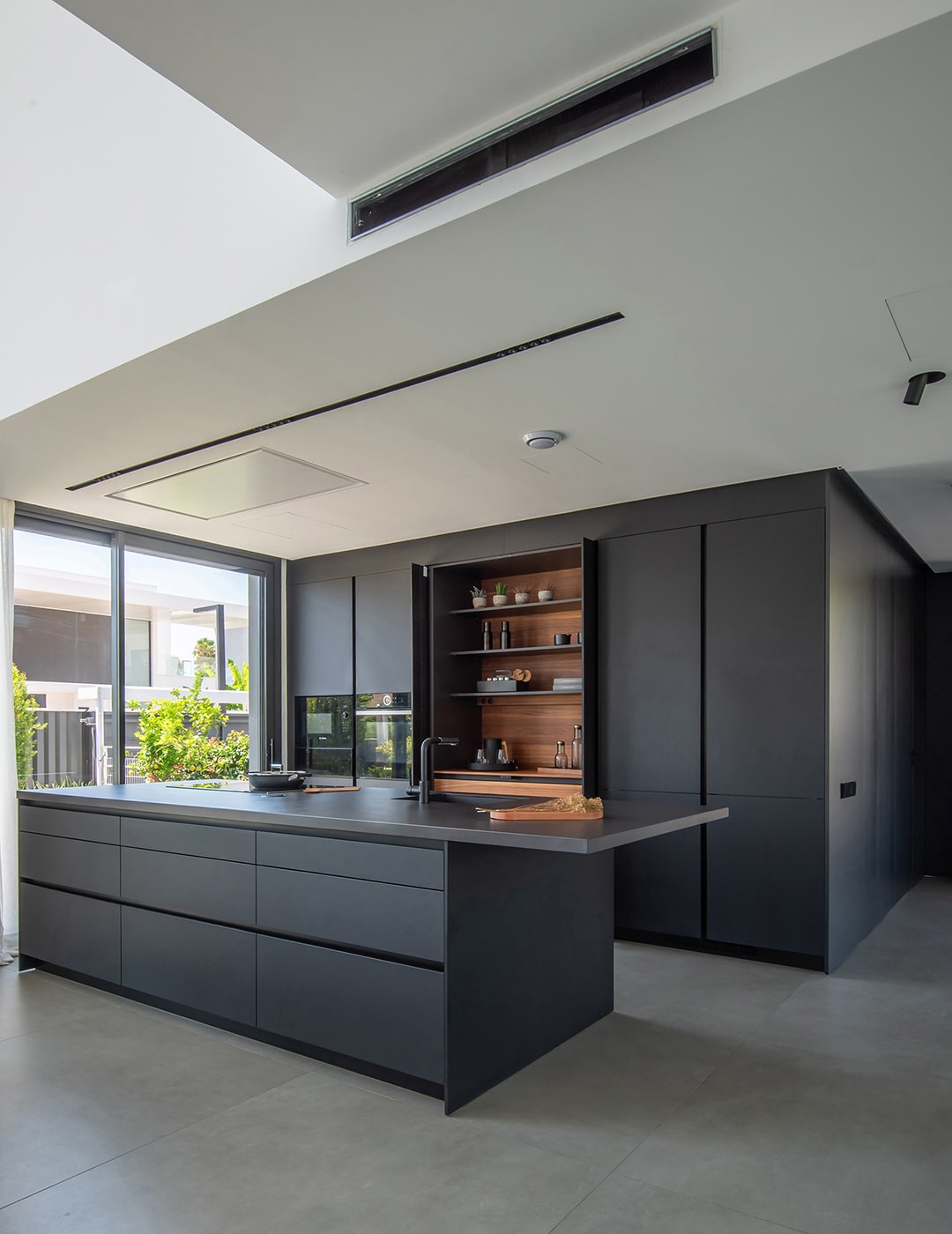 Cozinha preto e madeira aberta para a sala de estar com ilha central.