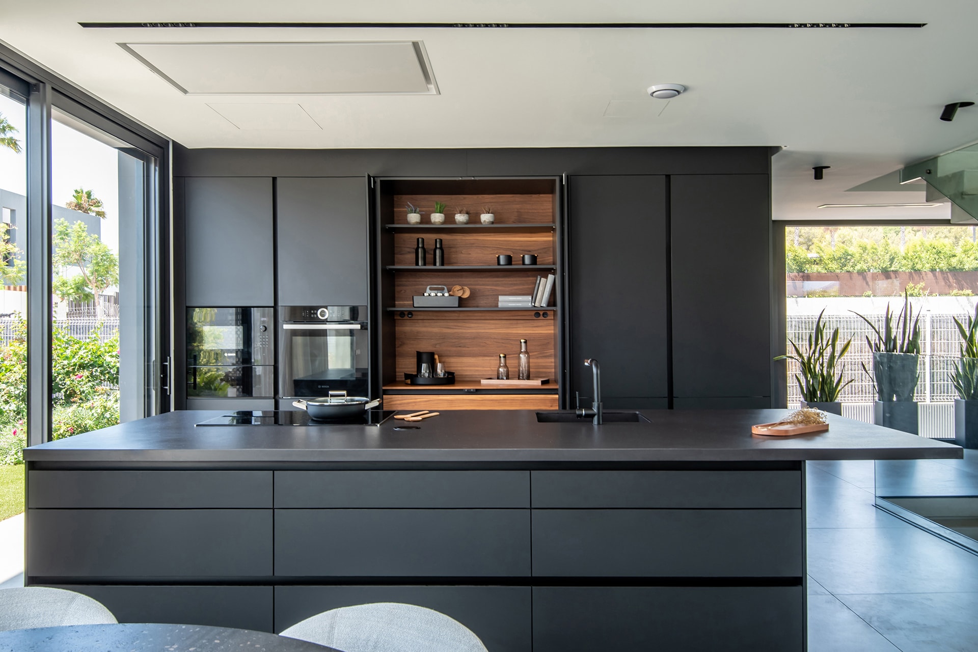 Cozinha Santos Preto Seda com ilha central e móveis com acabamento Fine.