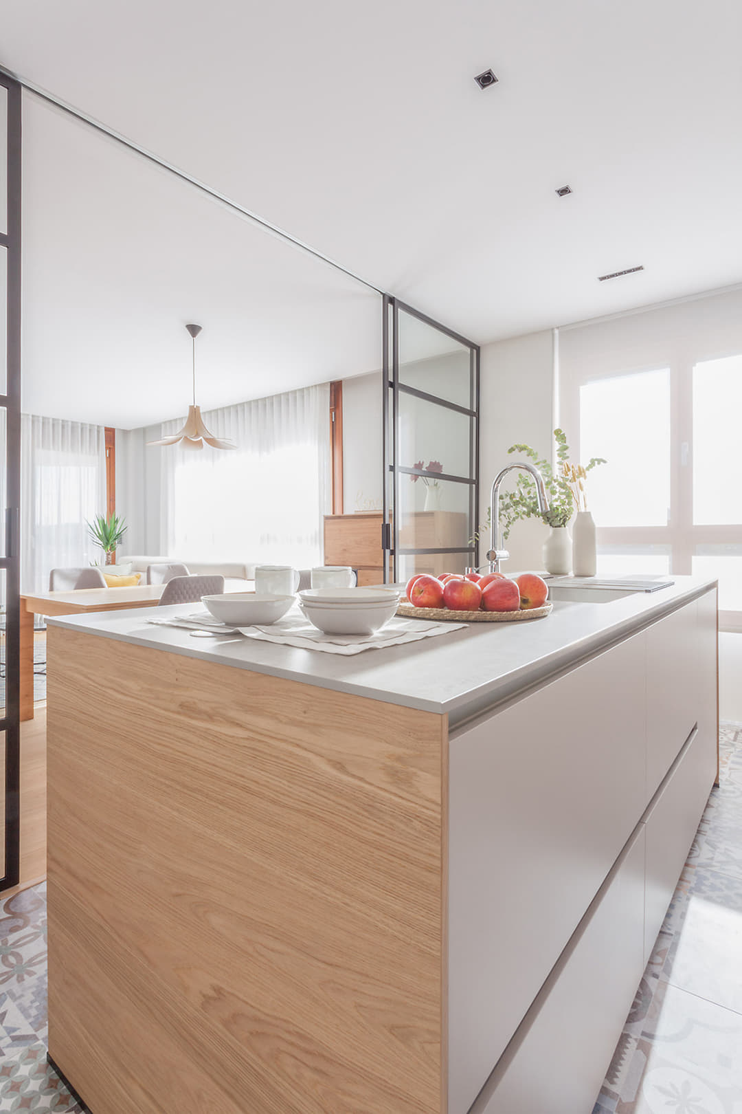 Isla de cocina abierta al salón comedor con cerramiento acristalado diseñada por Santos.