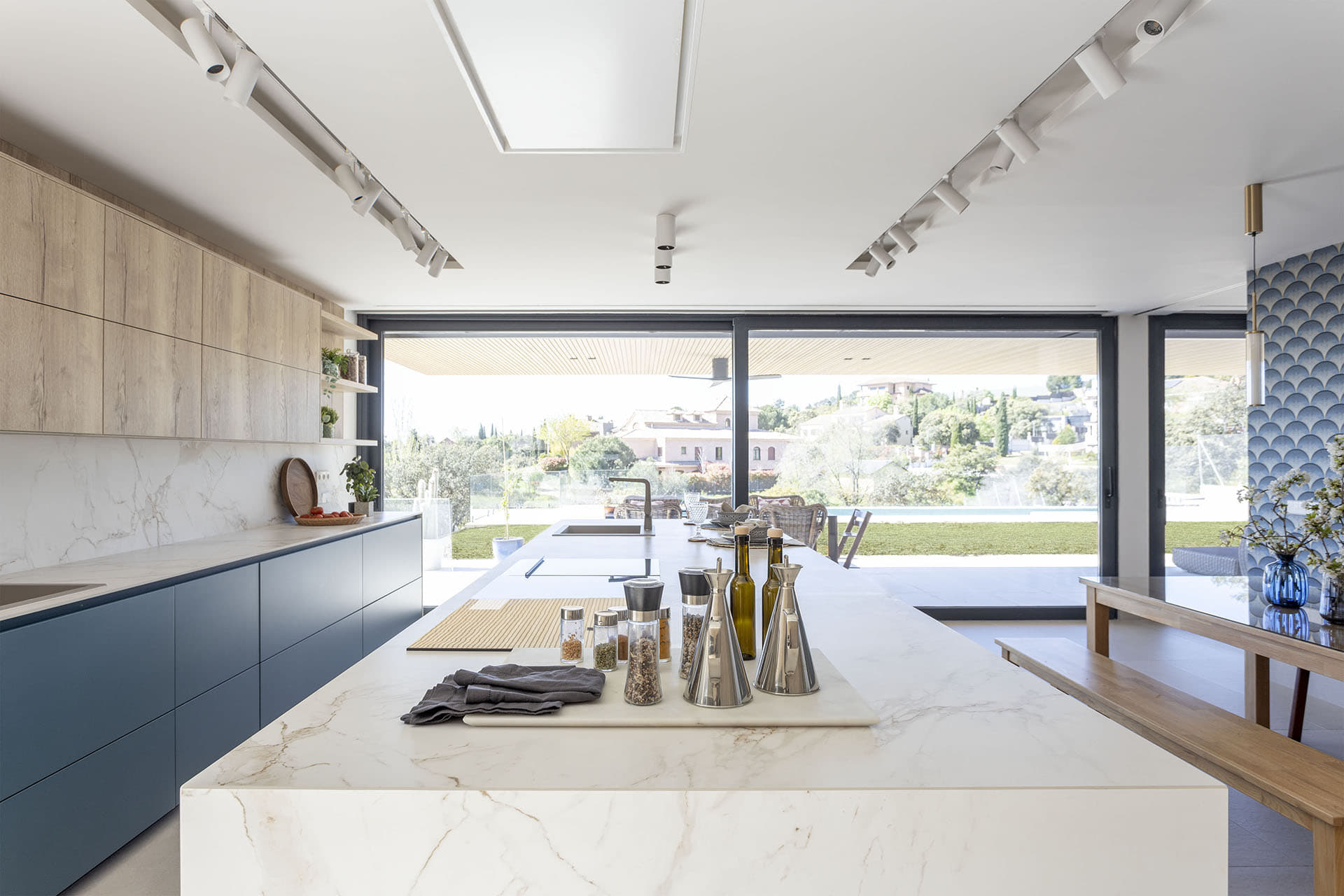 Isla de cocina con encimera blanca en cocina Azul Cosmos Seda Mate diseñada por Santos.