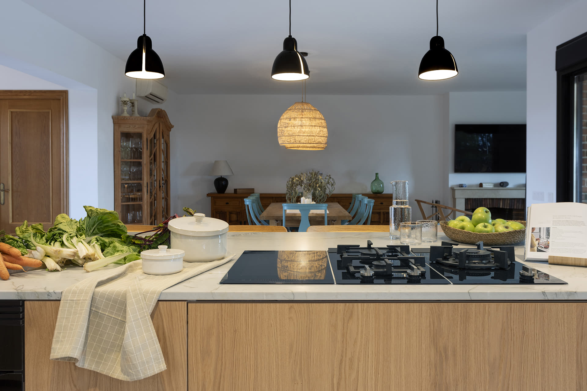Isla de cocina con encimera blanca y muebles en madera diseñada por Santos.