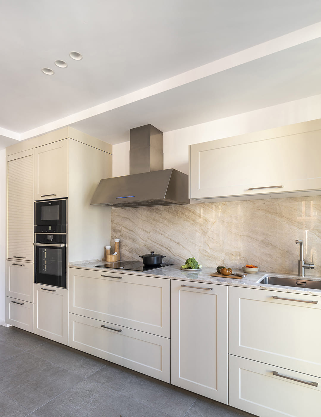 Cocina blanca Santos abierta al salón con electrodomésticos integrados en columna.