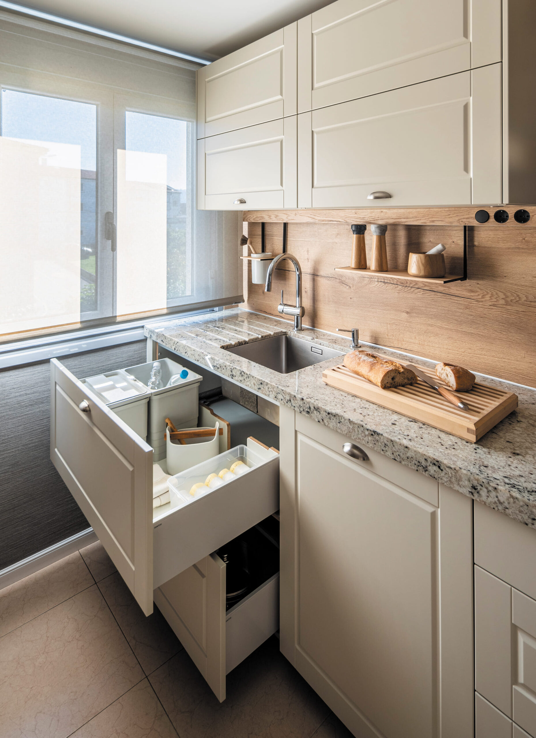 Muebles de almacenamiento con cajones en una cocina Santos blanca con acabados en madera.