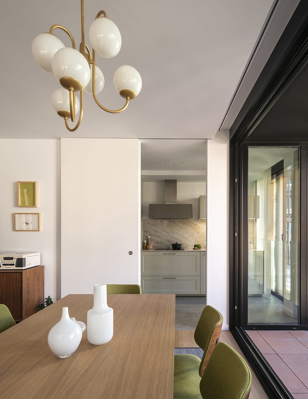 Vista del salón con puerta corredera que da acceso a una Cocina blanca Santos.