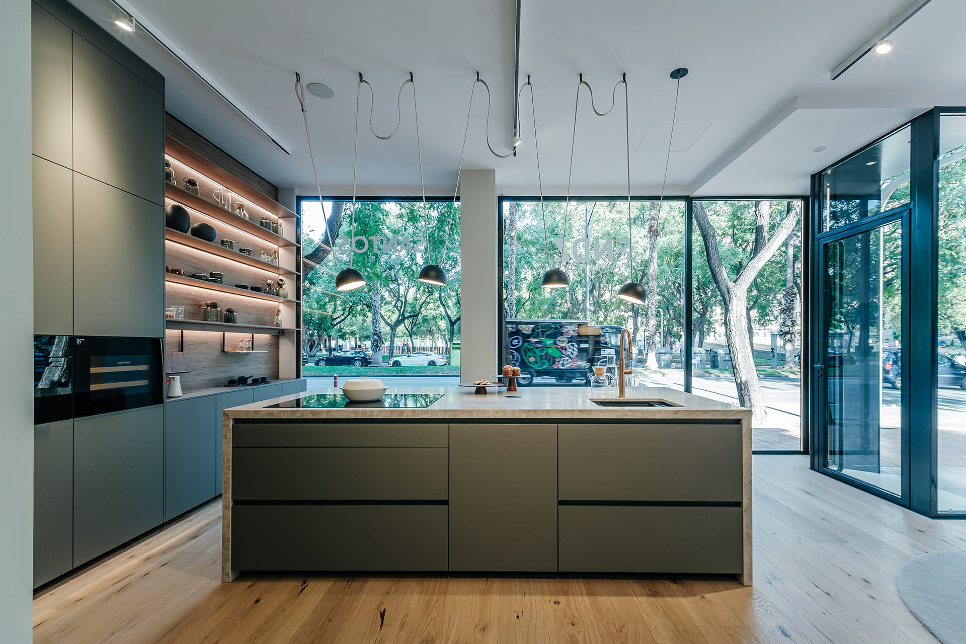 Cocina gris con isla y salón comedor en la nueva exposición de Cocinas Santos en Murcia.