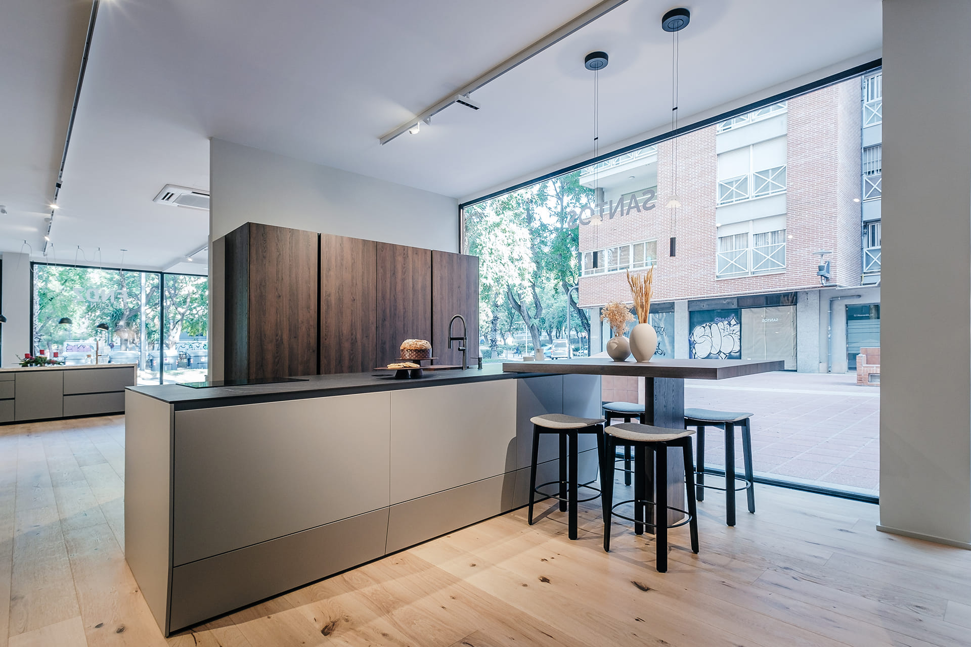 Cocina gris y madera con isla y barra enla tienda de Cocinas FNDZ, distribuidor de Santos en Murcia.