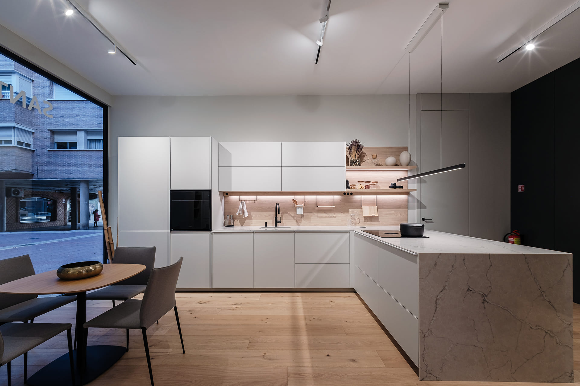 Cocina gris con península y lavandería anexa en el showroom de Cocinas FNDZ.