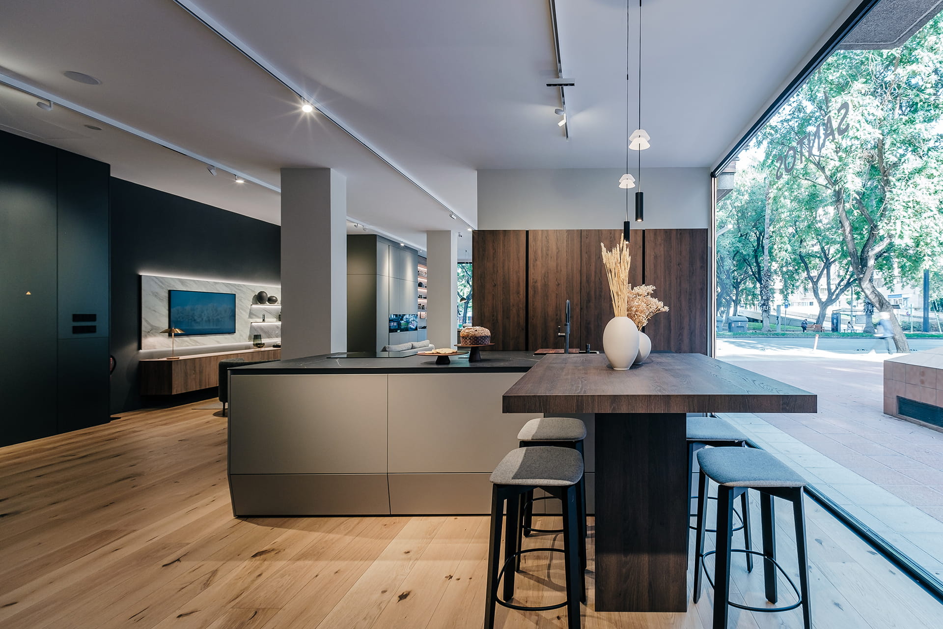 Cocina gris y madera abierta a sala de estar en el nuevo showroom de Cocinas Santos en Murcia.