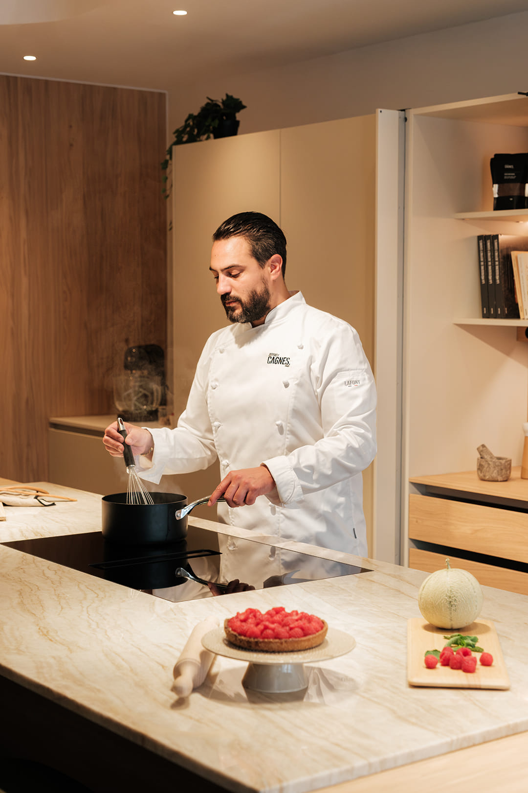 O chef Jeffrey Cagnes prepara um prato na placa de indução integrada na ilha de cozinha concebida pela Santos Paris.