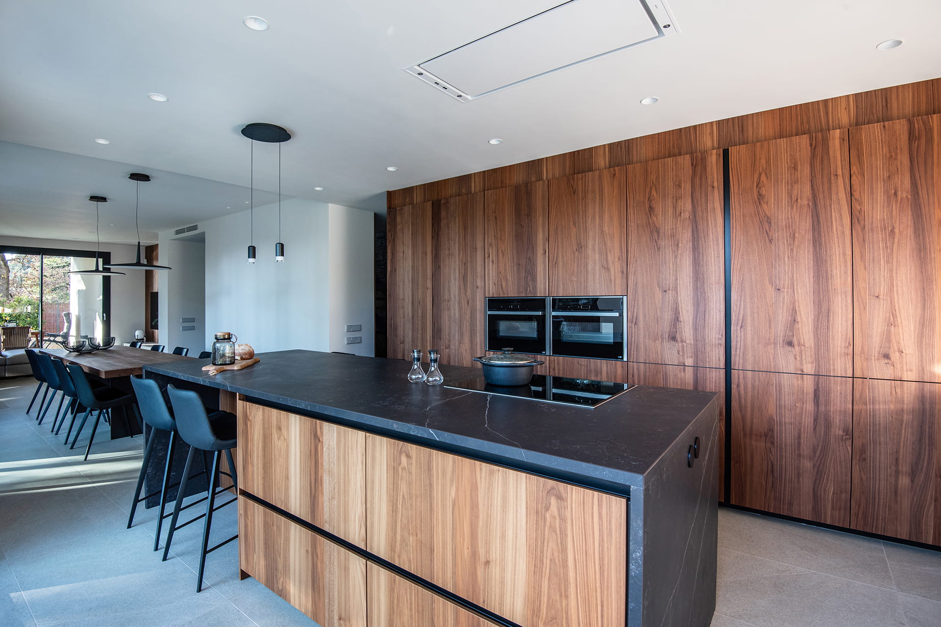 Cocina abierta al comedor en blanco y madera con isla en un proyecto de Santos.