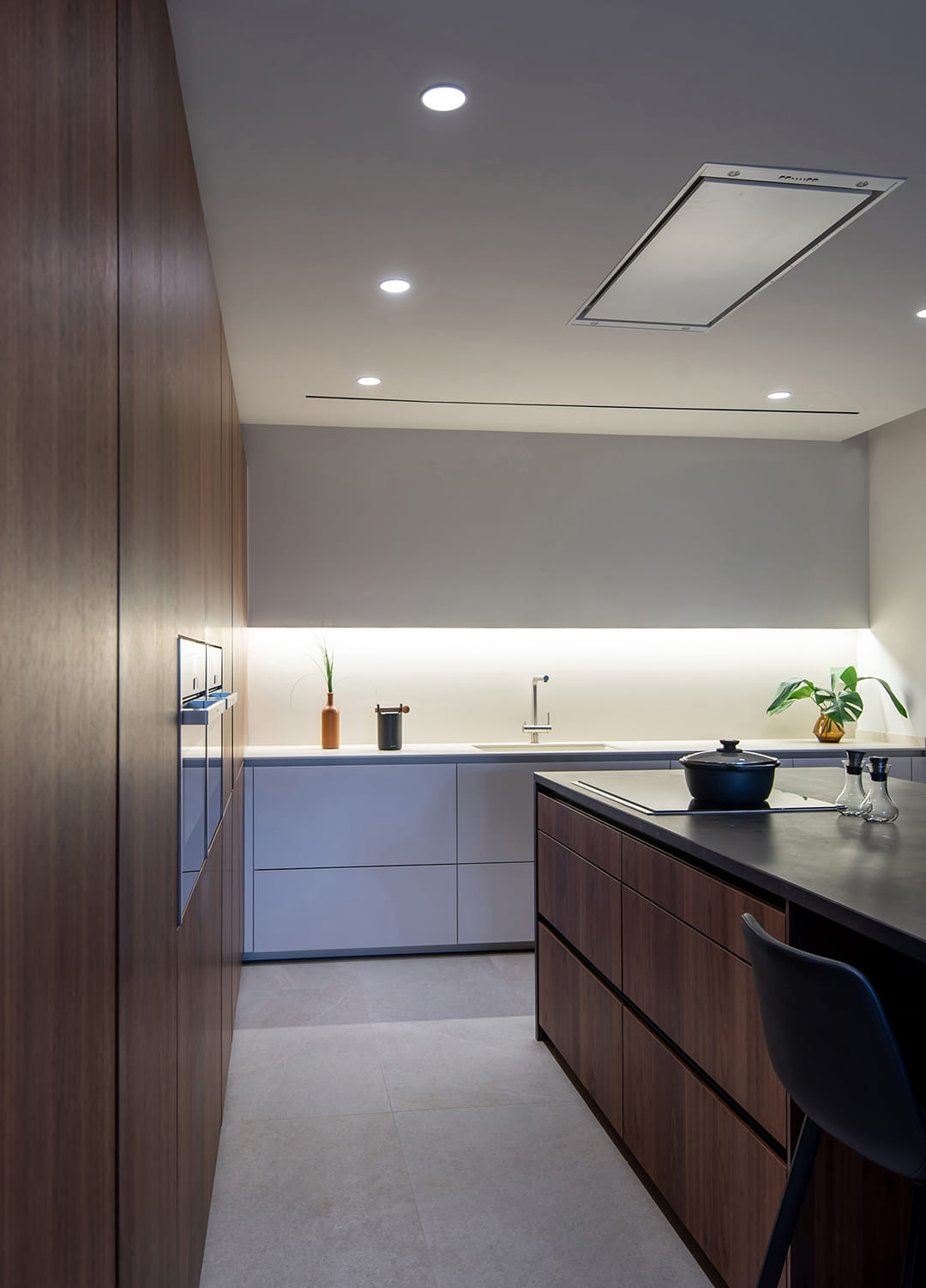 Cocina en blanco y madera con isla central e iluminación LED.