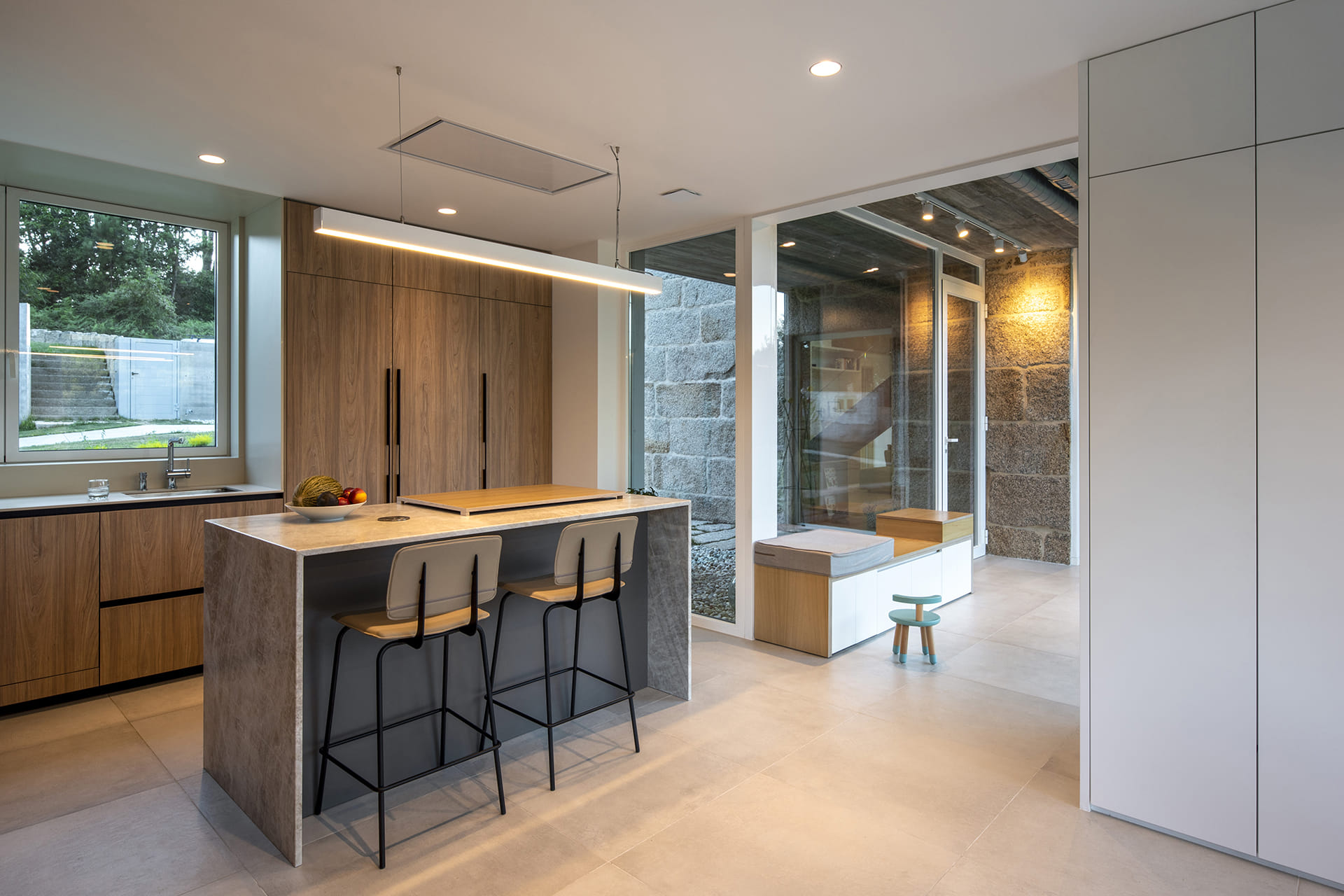 Cocina gris y madera con isla abierta al comedor en un proyecto de Santos.