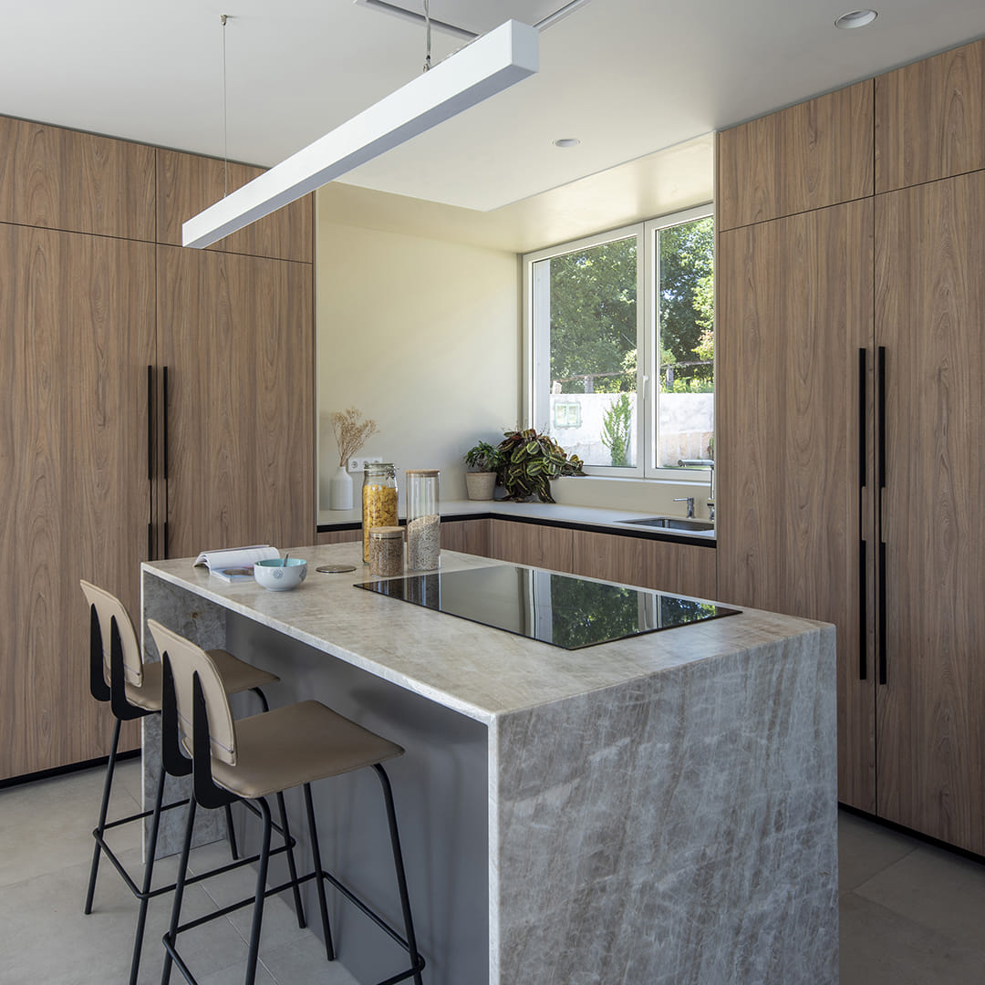 Cocina gris y madera con isla central y taburetes diseñada por Cocinas Santos.
