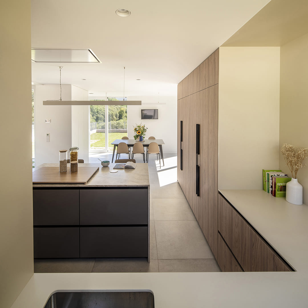 Vista de cocina gris y madera en L con isla central diseñada por Santos.