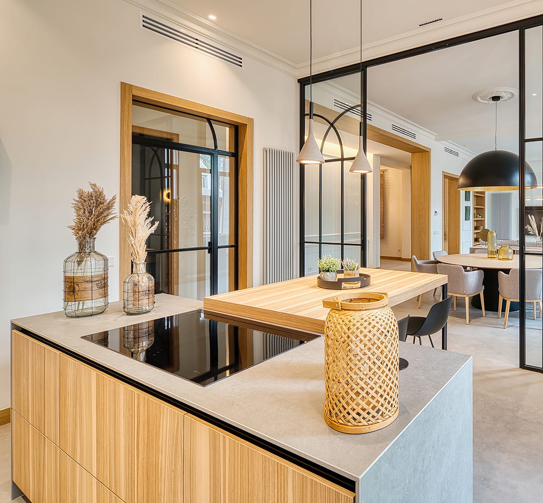Isla de cocina con barra de madera en una cocina abierta al salón diseñada por Santos.