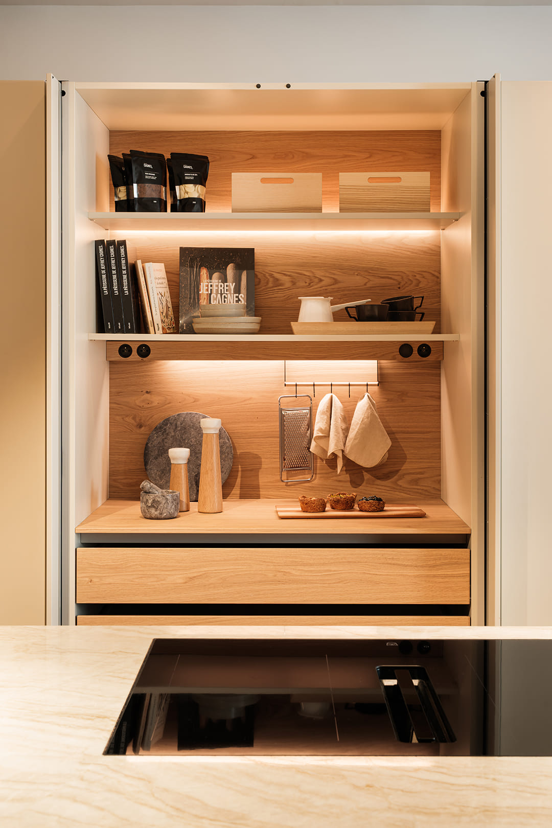 Ilha de cozinha com placa de indução integrada e armário escamoteável em coluna concebida pela loja de cozinhas Santos em Paris.