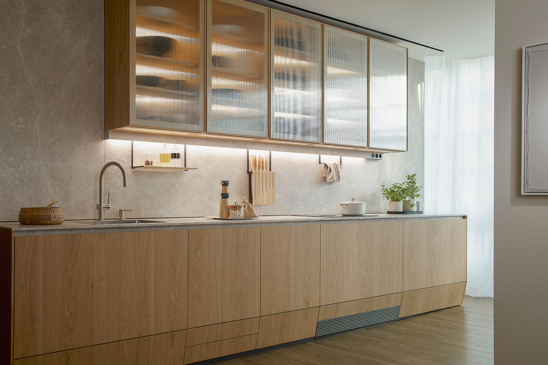 Cocina de madera con estantes y vitrinas con iluminación interior en un diseño de Santos.