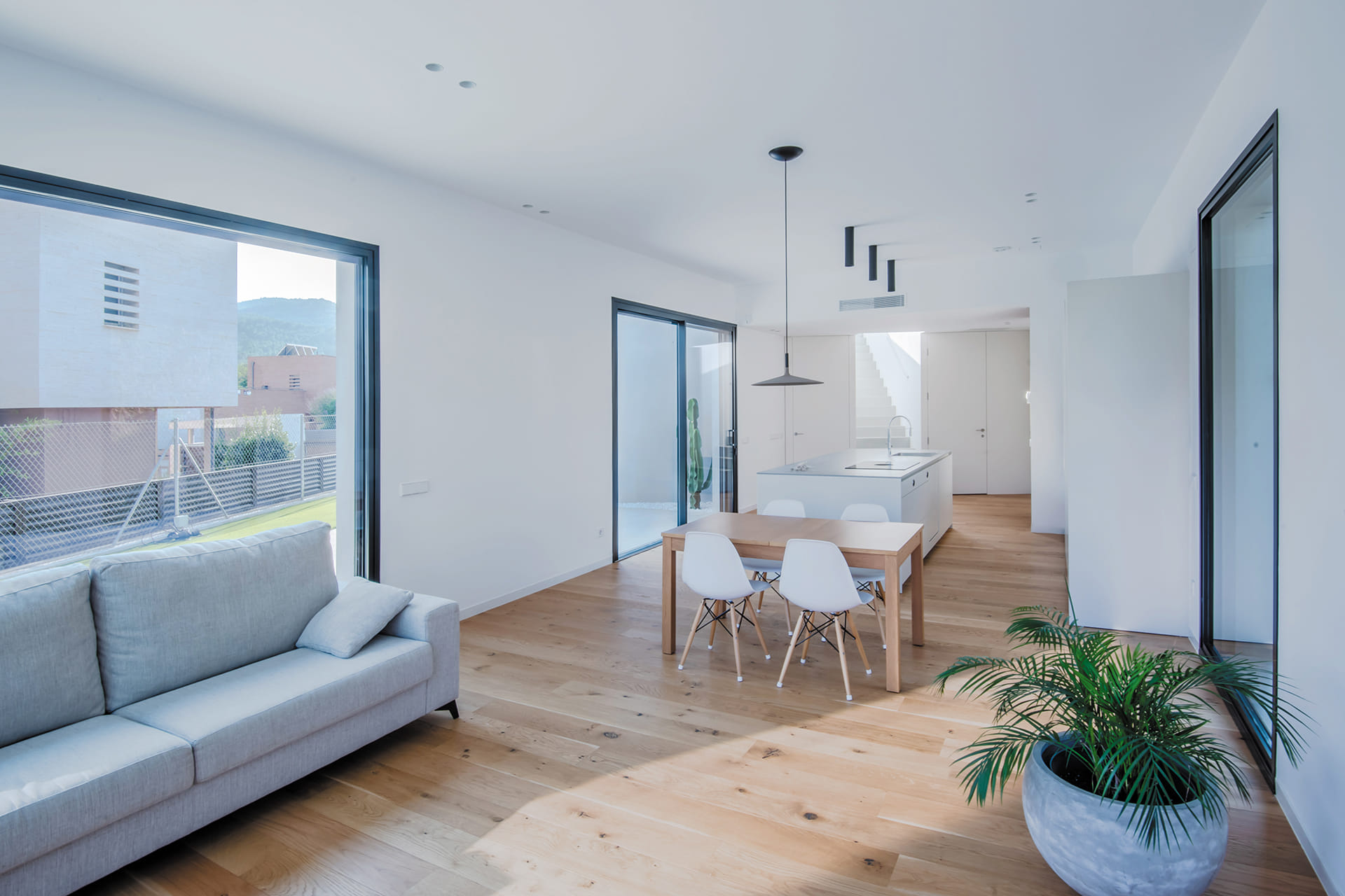 Cocina blanca con isla central abierta al salón en un proyecto de Santos.
