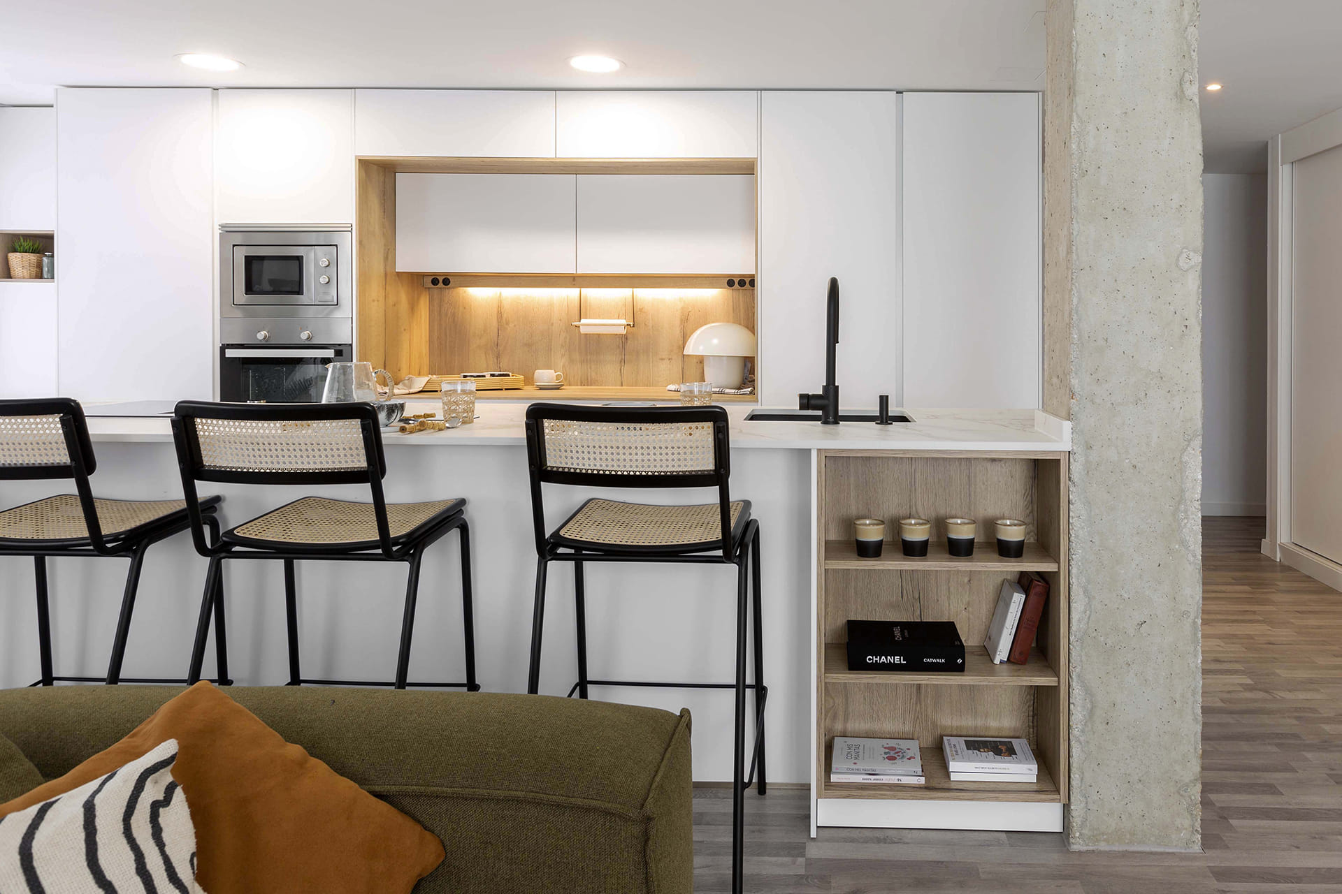 Cocina blanca con isla e iluminación superior sobre la encimera.