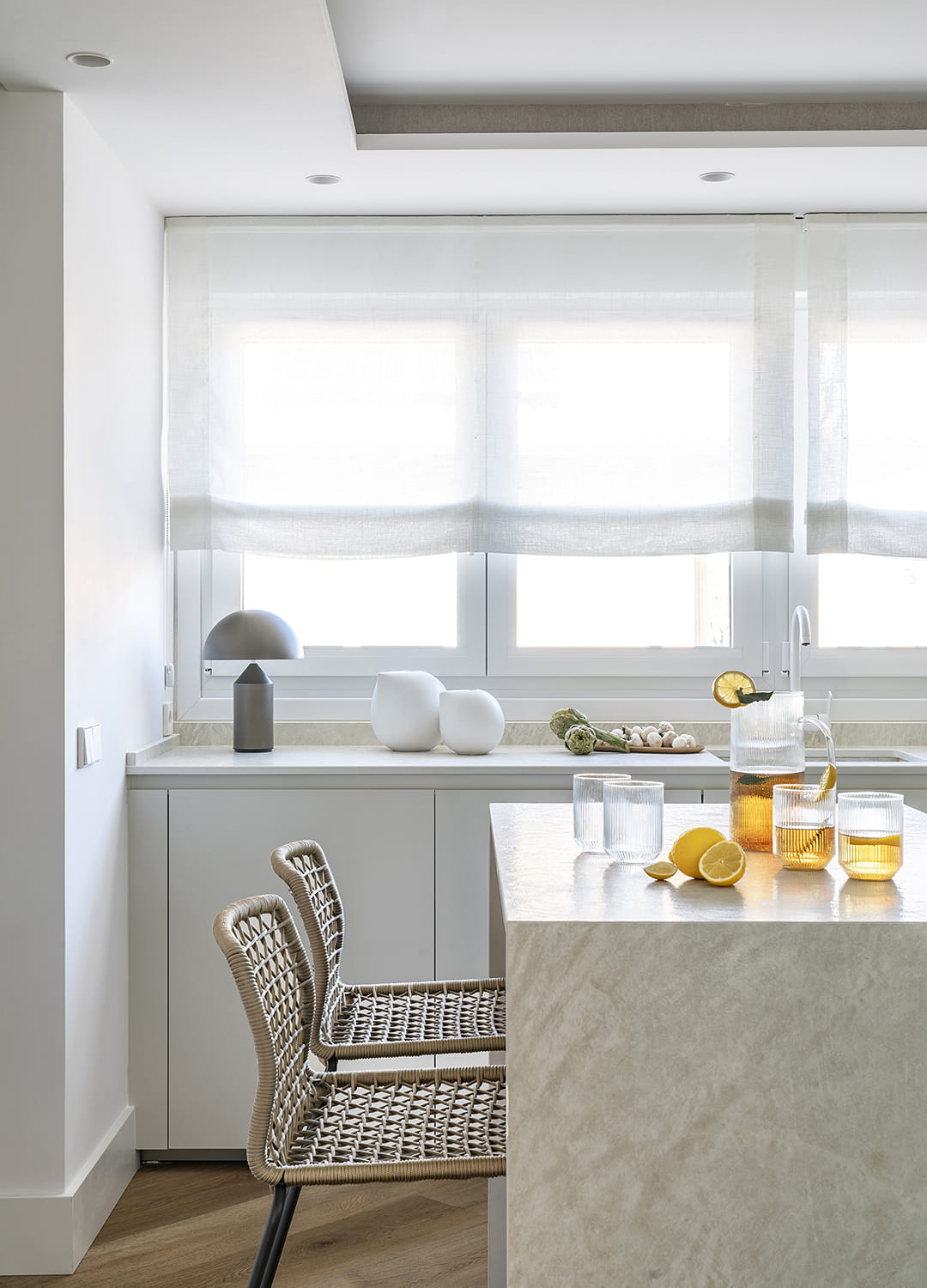 Cocina blanca Santos con isla central y barra con taburetes.
