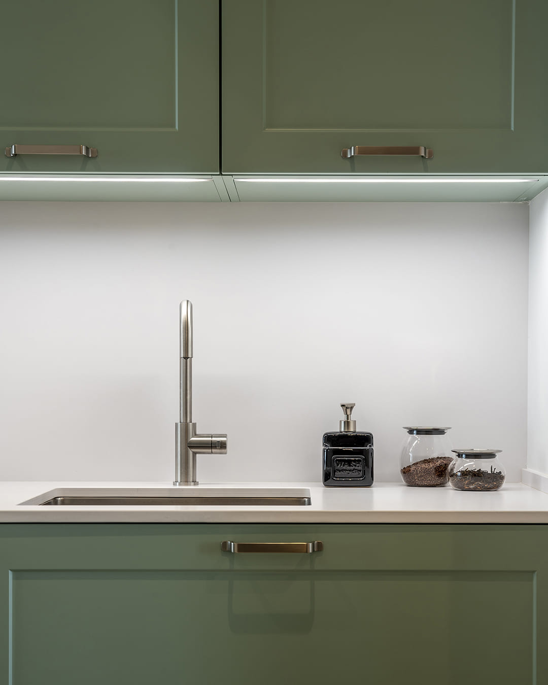 Zona del fregadero con iluminación superior en una cocina verde de Santos.