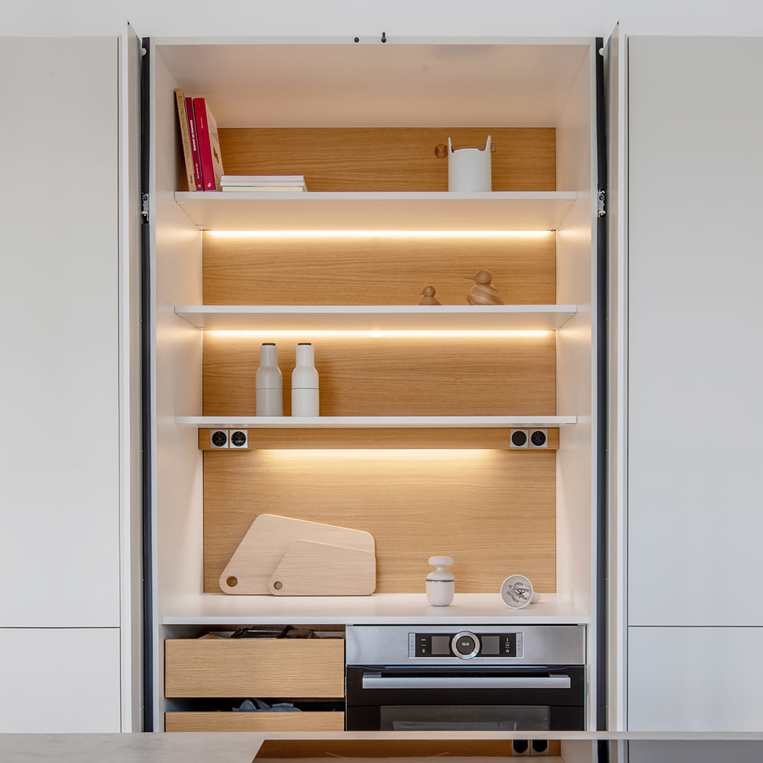 Armario con puertas escamoteables e iluminación interior y electrodomésticos en una cocina Santos.
