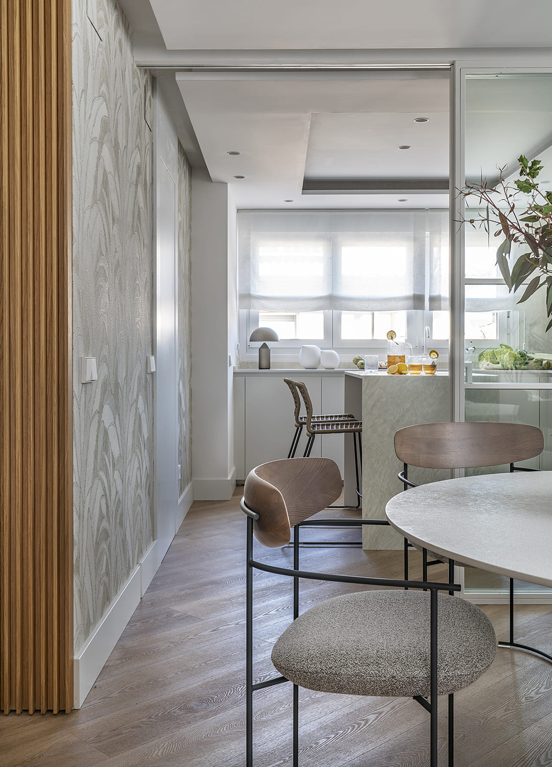 Cocina blanca con isla y muebles escamoteables en un proyecto diseñado por Cocinas Santos.
